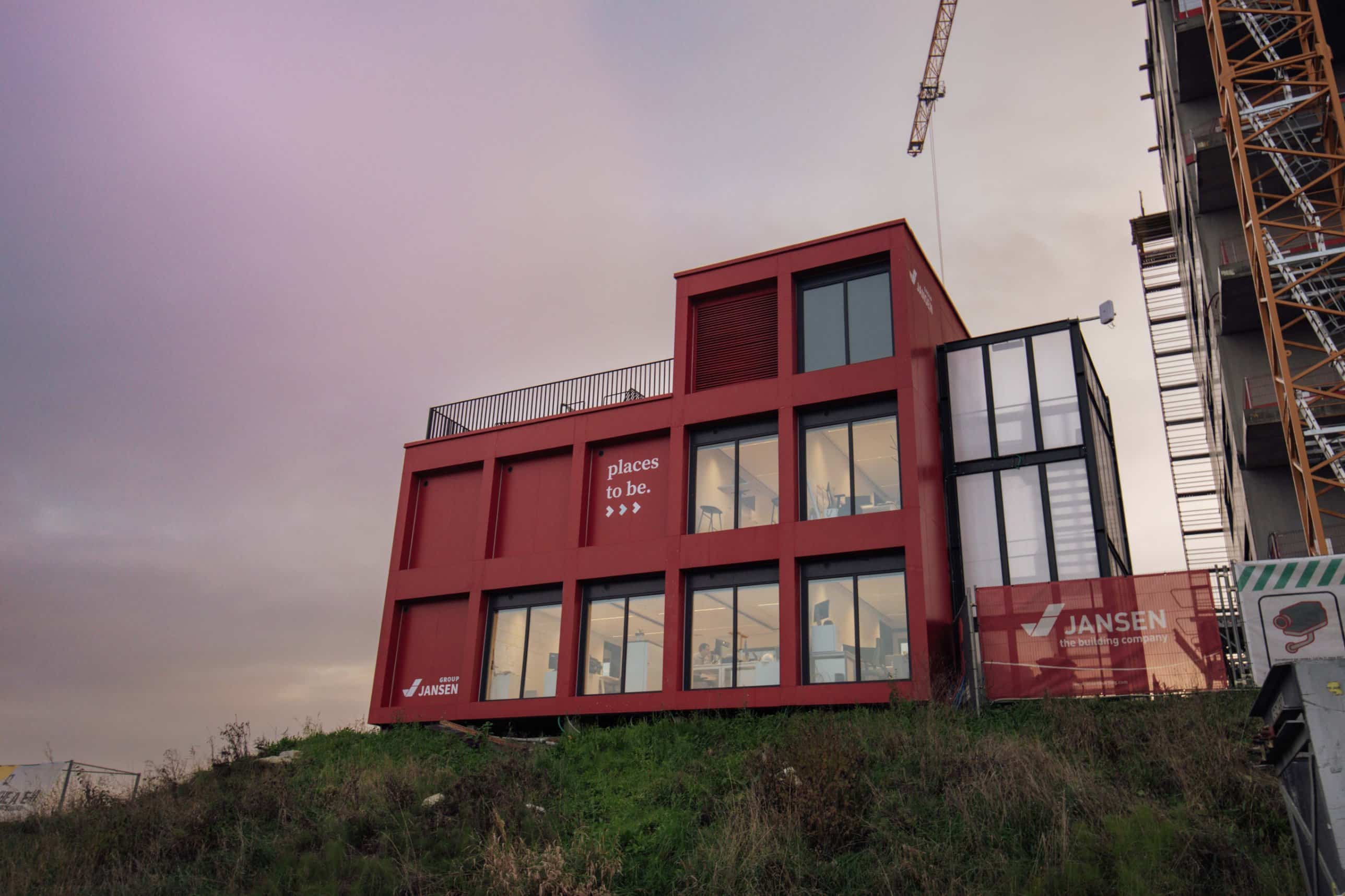 Rode werfkeet van Group Jansen met opschrift places to be naast een bouwwerf